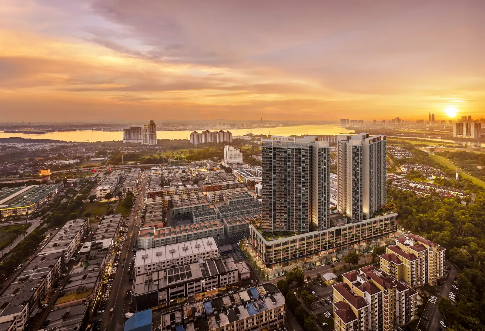 Aerial golden-hour view of The Straits View DUO twin towers above a retail podium in Permas Jaya, Johor Bahru, with the Straits of Johor in the background